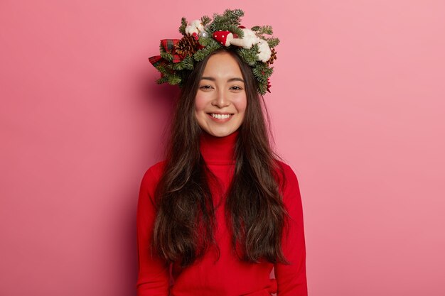 Adorable young lady smiles pleasantly wearing festive wreath on head