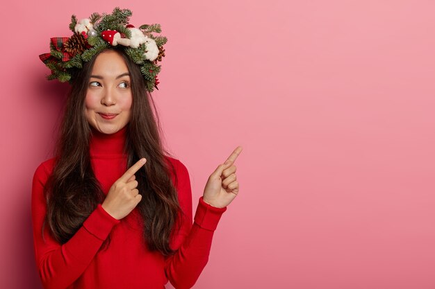 Adorable young lady smiles pleasantly wearing festive wreath on head