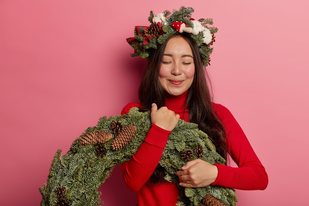 Adorable young lady smiles pleasantly wearing festive wreath on head