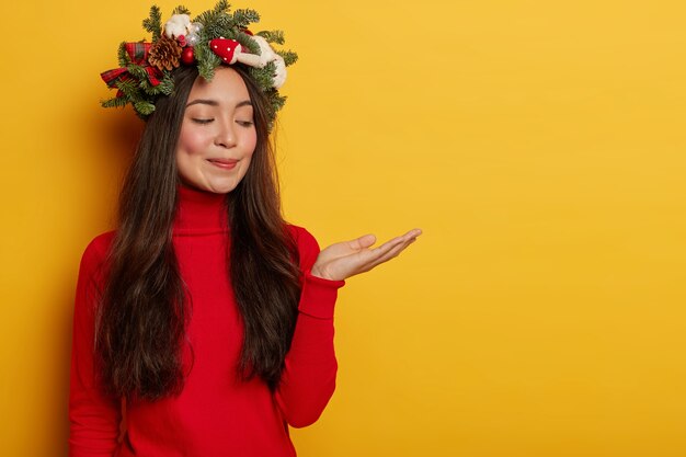 Adorable young lady smiles pleasantly wearing festive wreath on head