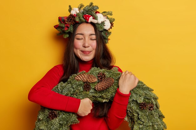 Adorable young lady smiles pleasantly wearing festive wreath on head