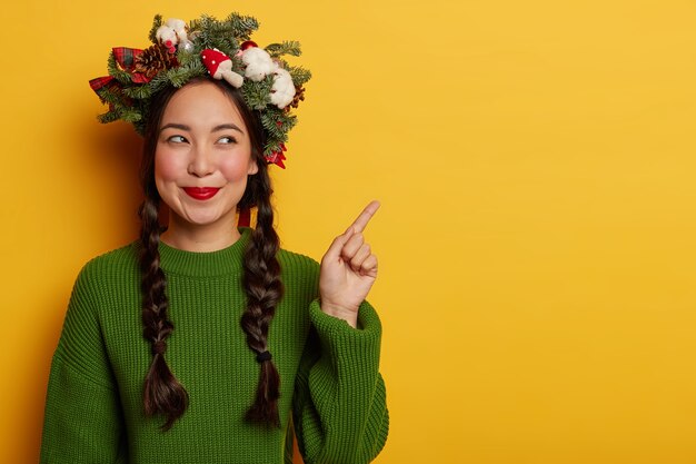 Adorable young lady smiles pleasantly wearing festive wreath on head