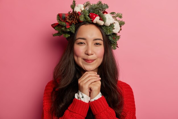 Adorable young lady smiles pleasantly wearing festive wreath on head