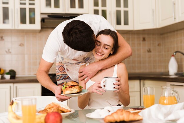 Adorable young man serving breakfast with girlfriend