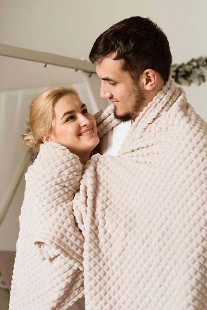 Adorable young man and woman covered in a blanket