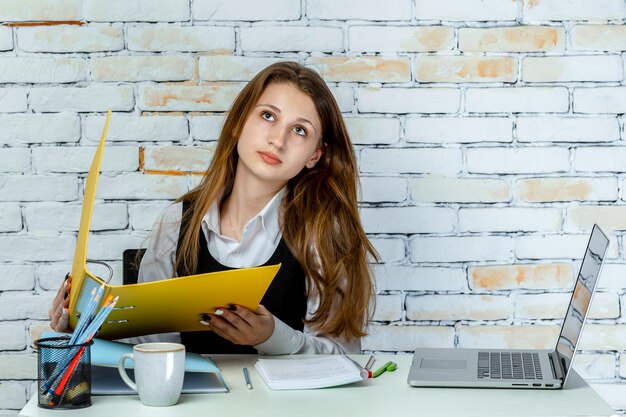 Adorable young student stand on white background and hold notebook while thinking High quality photo