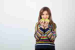 Free photo adorable young woman in casual clothes holding green apples on white background.