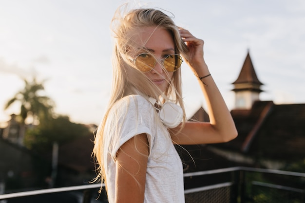 Free photo adorable young woman in yellow sunglasses posing on sky background.