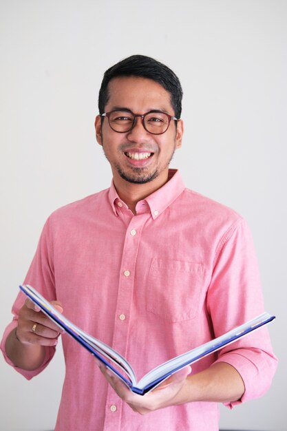 책을 들고 자신감 있게 웃고 있는 성인 아시아 남자 프리미엄 사진