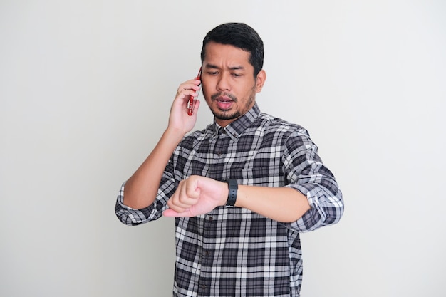시계를 보면서 전화로 누군가와 이야기하는 성인 아시아 남자 프리미엄 사진