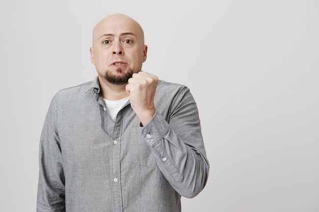 Adult bald man scolding with raised fist, threatening