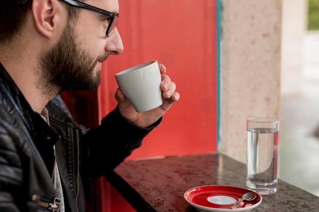 Free photo adult bearded man drinking beverage at cafe