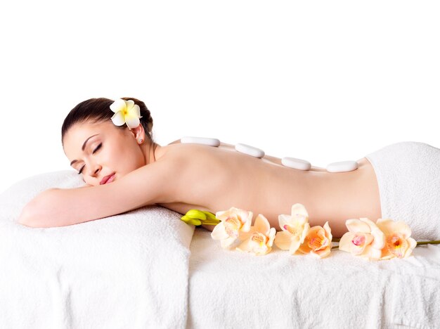 Adult beautiful woman relaxing in spa salon with hot stones on back