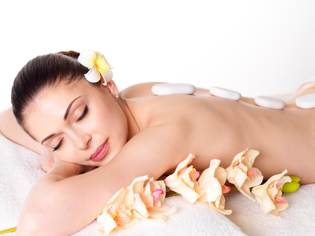 Adult beautiful woman relaxing in spa salon with hot stones on back