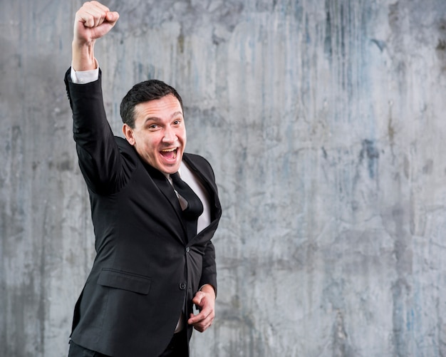 Adult businessman raising fist and smiling