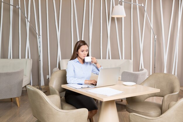 Взрослый бизнесмен работает на ноутбуке в кафе