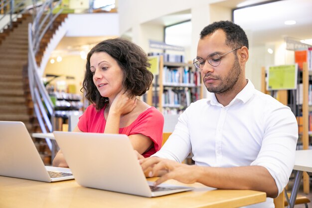 Adult college students discussing project while working