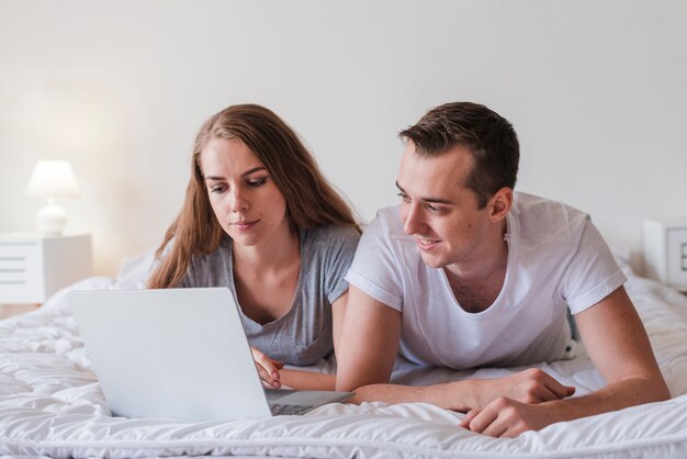 Adult couple browsing laptop together on bed