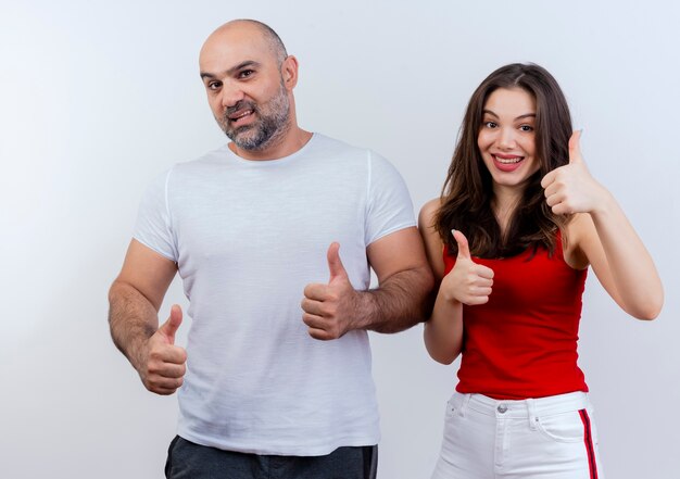 Adult couple confident man and impressed woman both showing thumbs up and looking 