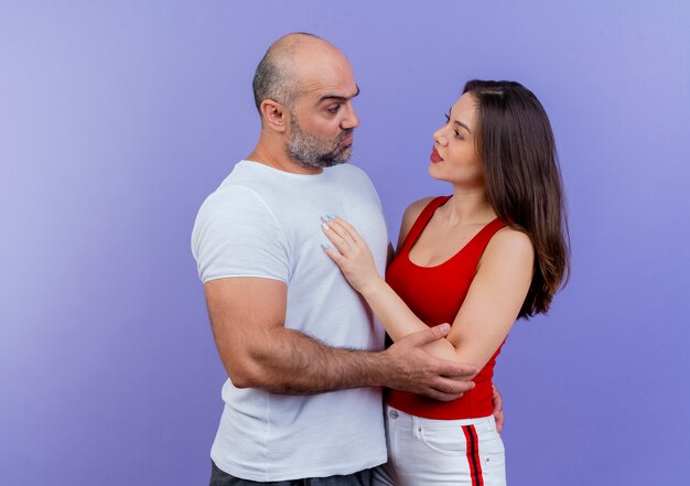 Взрослая пара сомневается, что мужчина кладет руку женщине на спину и касается ее руки, и она кладет руку ему на грудь, глядя друг на друга