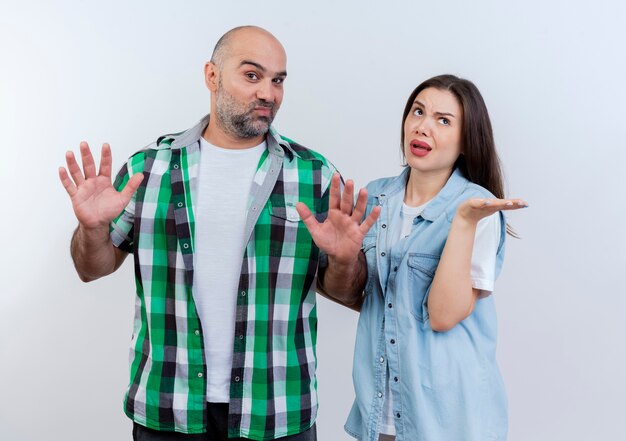 Adult couple impressed man showing empty hands looking and clueless woman looking up showing empty hand 