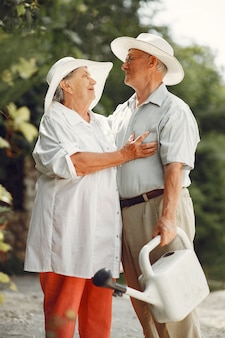 サマー​ガーデン​の​大人​の​カップル​。​白い​シャツ​を​着た​ハンサムな​先輩​。​帽子​を​かぶった​女性​。​家族​の​水​やり​。