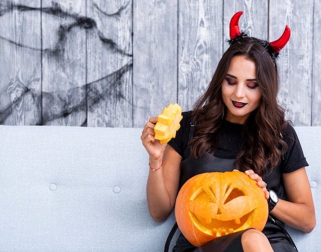 Adult evil woman holding carved pumpkin
