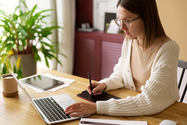 Foto gratuita illustratore femminile adulto che lavora su un dispositivo tablet