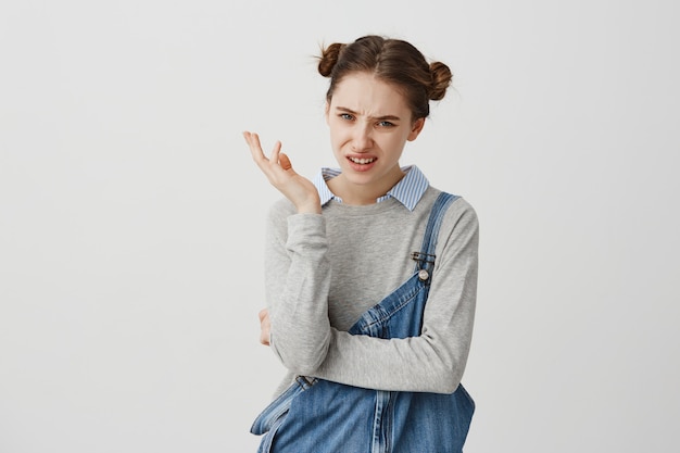 Free photo adult girl 30s gesturing skeptically expressing disagreement with facial expressions. female employer with childish hairstyle being disappointed with final results. reactions, attitude concept