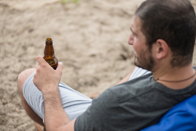 Adult guy resting on beach with beer