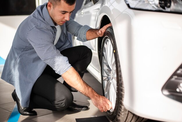 車のタイヤをチェックする成人男性