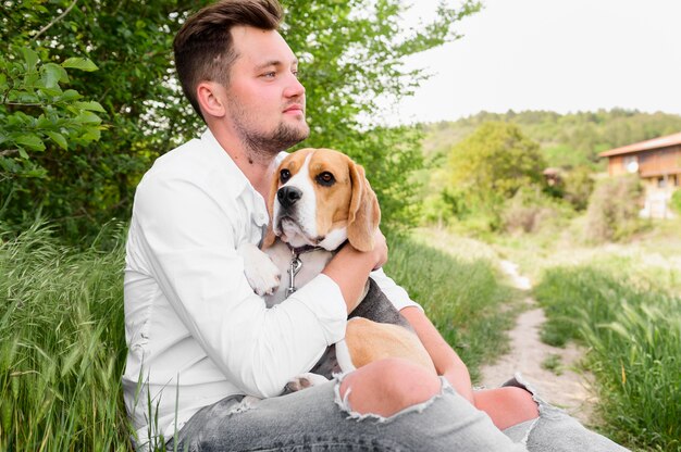 Adult male holding his dog in the park