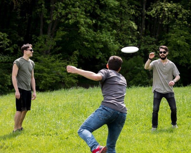 Free photo adult male throwing frisbee for friend in park