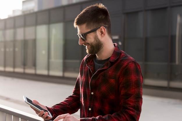 Foto gratuita maschio adulto che cammina e che utilizza telefono cellulare