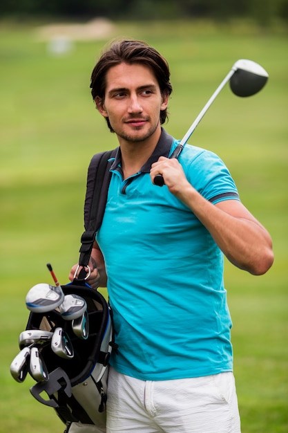 Adult man carrying golf clubs outdoors