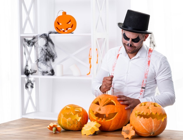 Foto gratuita uomo adulto che intaglia le zucche per halloween