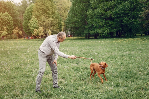 Взрослый мужчина в парке летом с собакой