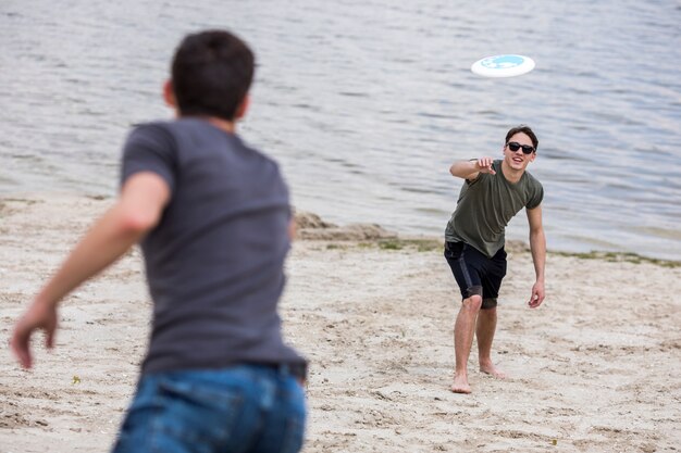 Adult man throwing frisbee for friend on beach