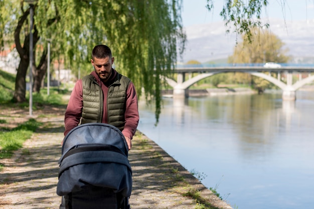 Foto gratuita uomo adulto che cammina con passeggino vicino al fiume