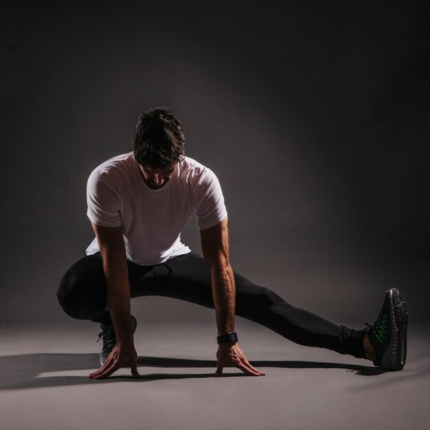 Adult man warming up on dark background