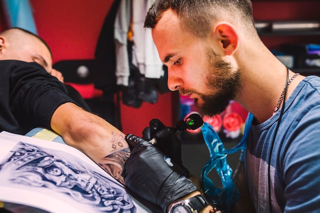 Adult man working with tattoo pen on arm
