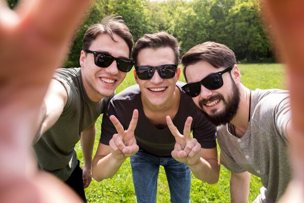 Adult men in sunglasses taking photo on smartphone