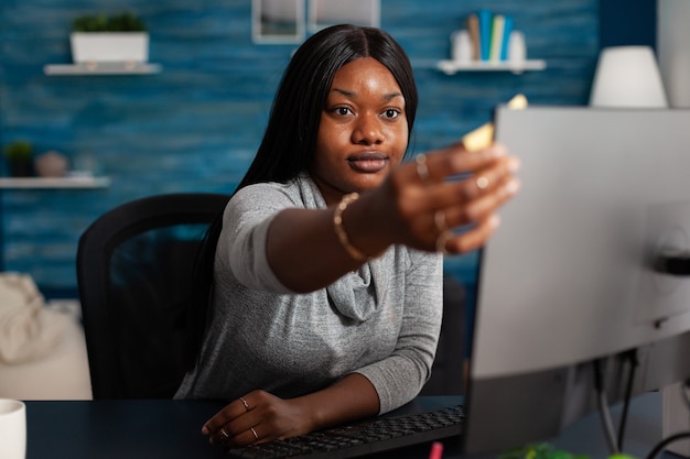 Adult putting sticky notes on monitor to work remotely