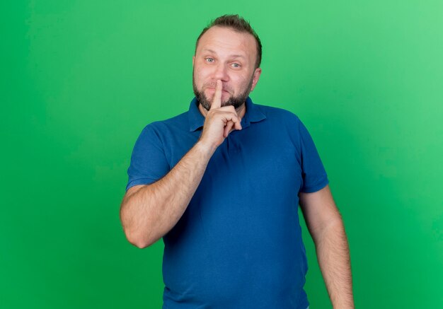 Взрослый славянский мужчина делает жест молчания изолирован на зеленой стене с копией пространства