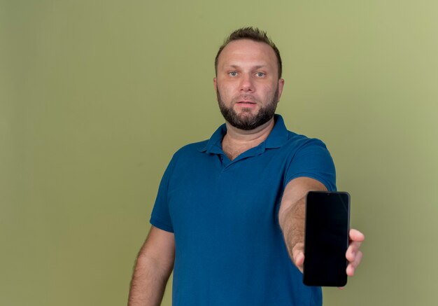 Взрослый славянский мужчина смотрит протягивая мобильный телефон