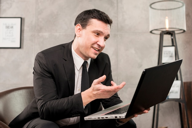 Adult smiling businessman browsing laptop at home