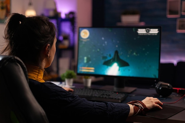 Взрослый использует клавиатуру и коврик для мыши, чтобы играть в видеоигры на компьютере. Геймер играет в онлайн-игру перед монитором с консолью управления и мышью на столе. Современный плеер с игровым оборудованием