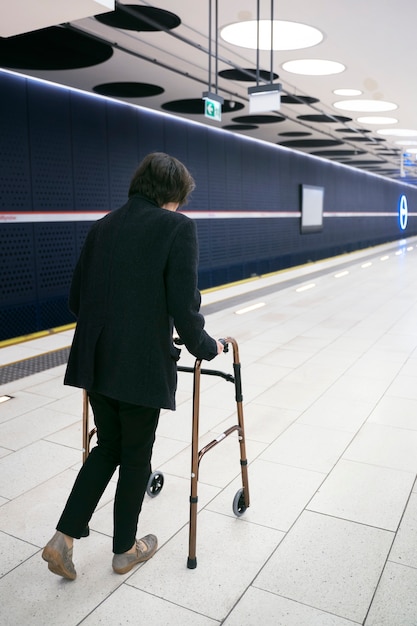 Бесплатное фото Взрослый с прогулочной рамой на станции метро полный кадр