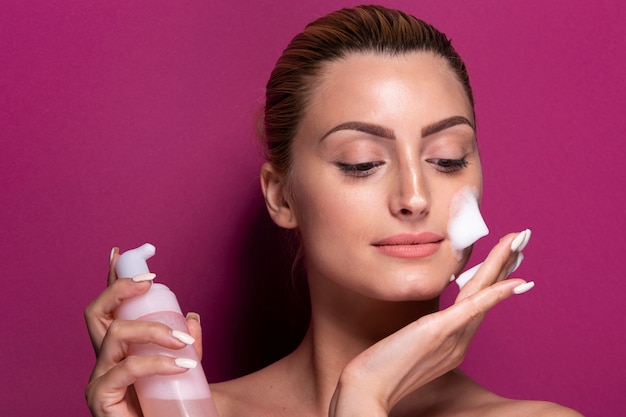 Adult woman applying moisturizer on her face