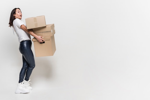 Adult woman carrying cardboard boxes with copy space